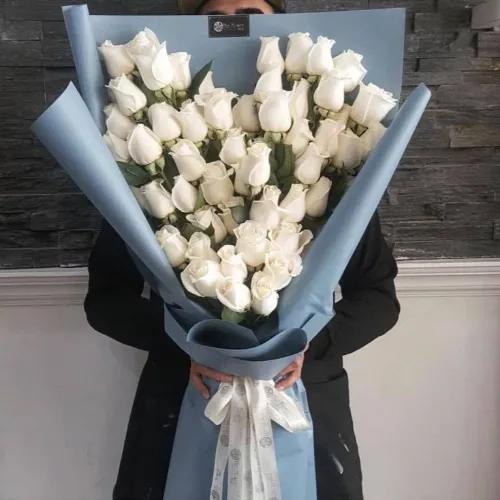 Hand Bouquet With White Roses Heart Shape In Blue Paper Wrapping