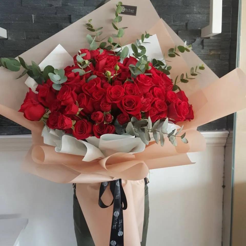 Hand Bouquet With Red Roses And Eucalyptus In Nude Paper Wrapping